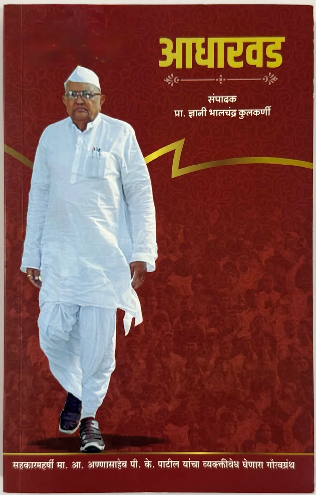Cover of Aadharwad, edited by Prof. Gyani Bhalchandra Kulkarni: Annasaheb in white khadi clothes walking in front of a crowd, on a deep red background