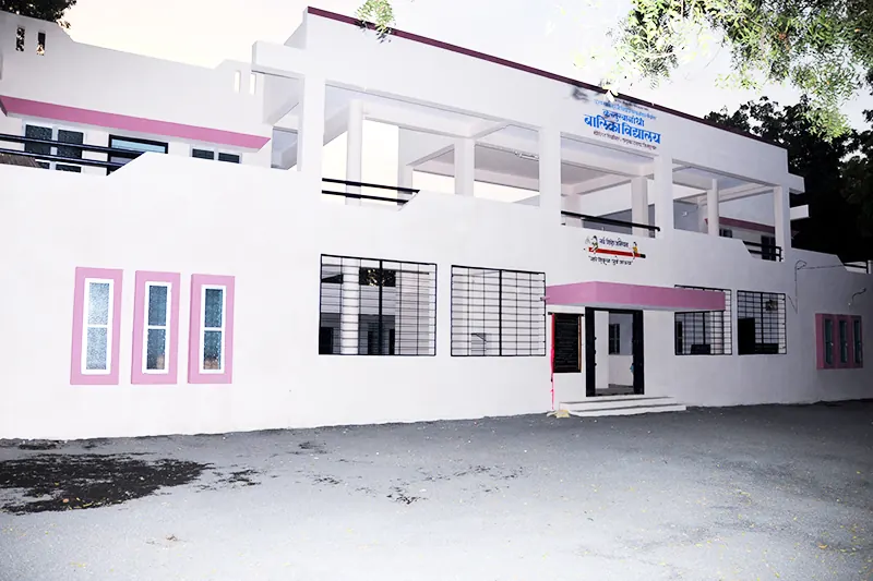 A white school building with pink-framed windows, decorated with garlands for an occasion